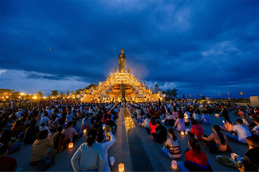 Du khách dâng đăng trước tượng Phật để cầu nguyện bình an 